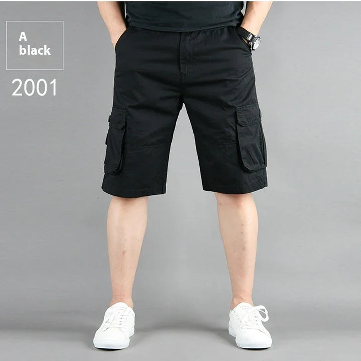 Man wearing black cargo shorts with pockets and white sneakers on gray background