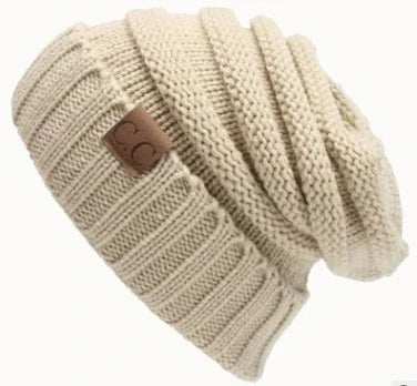 Beige knitted slouchy beanie hat with a ribbed cuff and brown leather CC logo patch