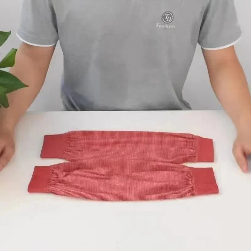 Person in gray t-shirt presenting two red stretchy arm sleeves on a white table with green plant visible