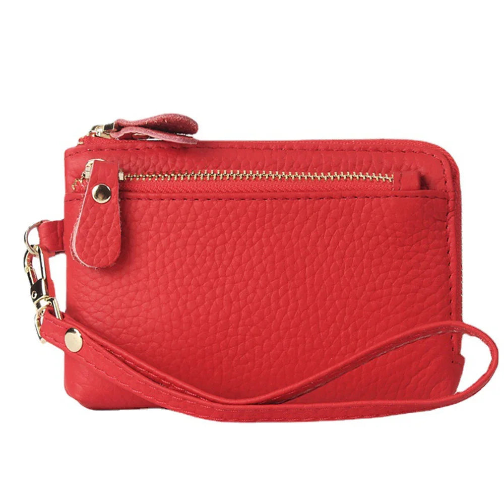 Red textured leather wristlet wallet with gold zipper and detachable strap isolated on white