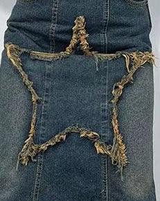Denim fabric with a large frayed star-shaped patch sewn on weathered blue jeans