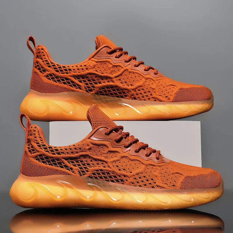Modern orange knitted sneakers with transparent orange cushioned soles on gray background