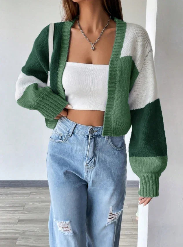 Woman wearing green and white colorblock knit cardigan with white crop top and ripped light blue jeans