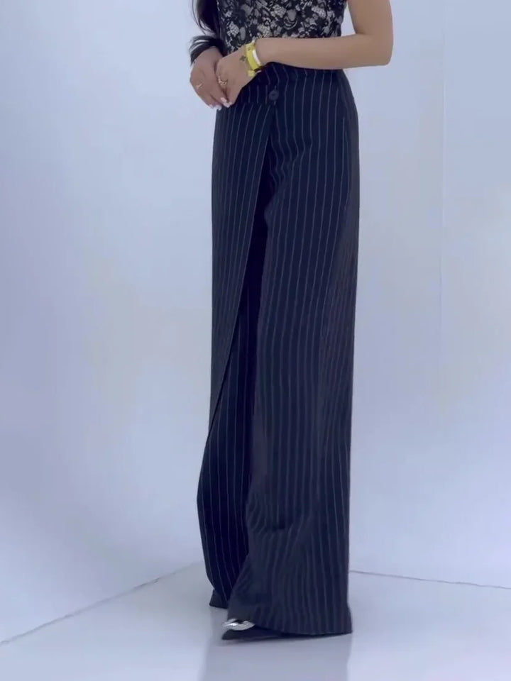 Woman wearing black pinstripe wide-leg pants and lace top in minimalist white studio