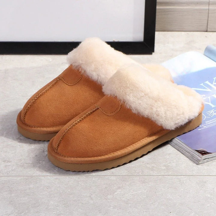 Brown suede slippers with thick white faux fur lining, placed on a tiled floor next to a blue magazine