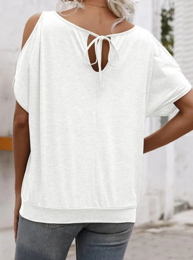 Woman wearing white cold shoulder casual top with back tie detail and grey jeans outdoors