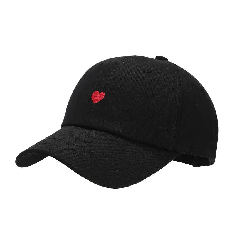 Black baseball cap with small embroidered red heart on front, adjustable back strap