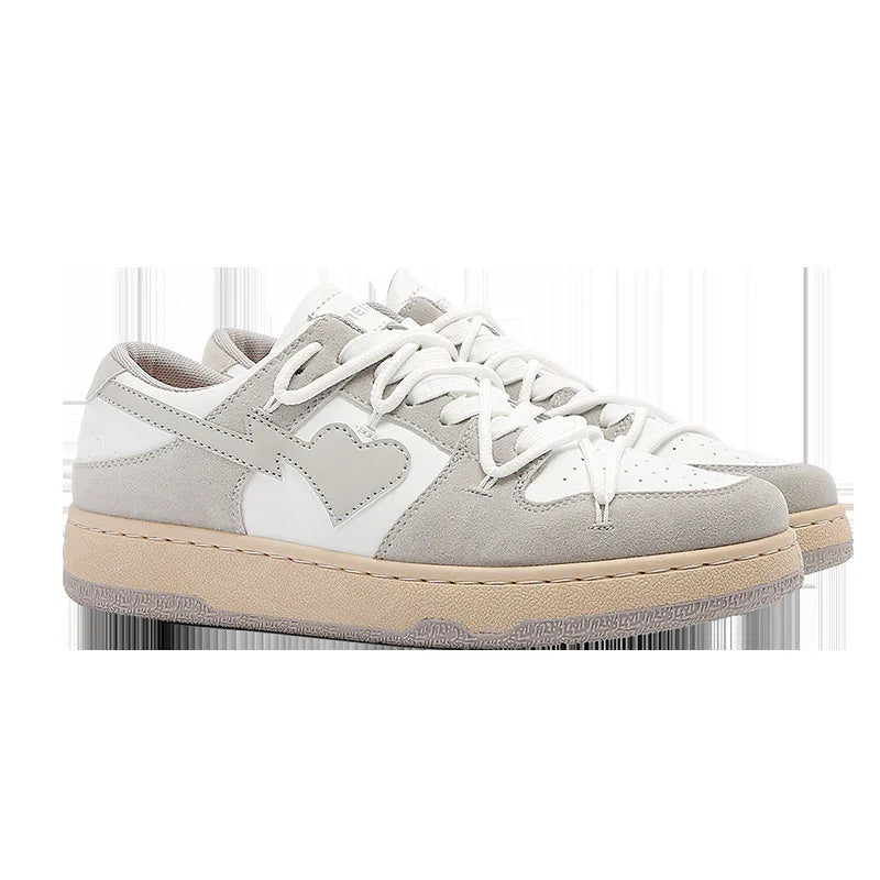 Pair of white and gray suede sneakers with heart design and beige soles on white background