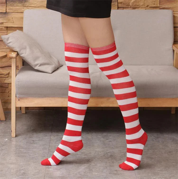 Legs wearing red and white striped knee-high socks indoors near sofa with beige cushion