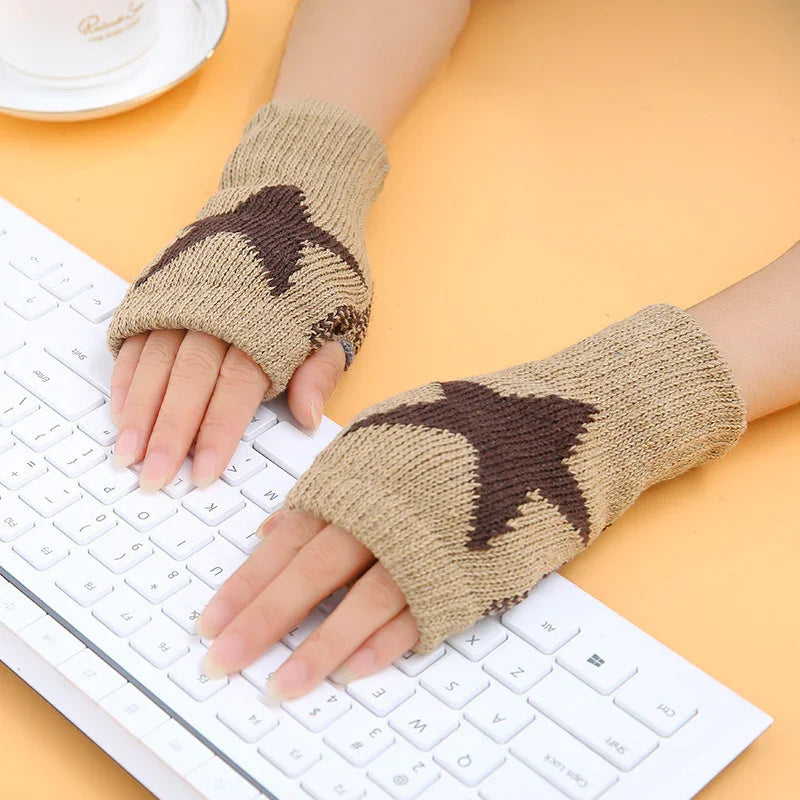 Hands wearing beige and brown star-patterned fingerless gloves typing on white keyboard on yellow surface