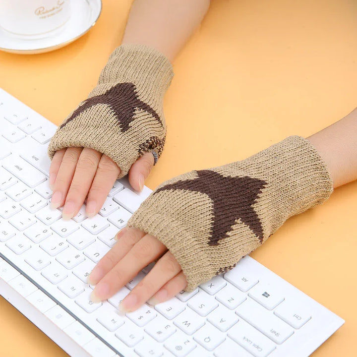 Hands wearing beige and brown star-patterned fingerless gloves typing on white keyboard on yellow surface