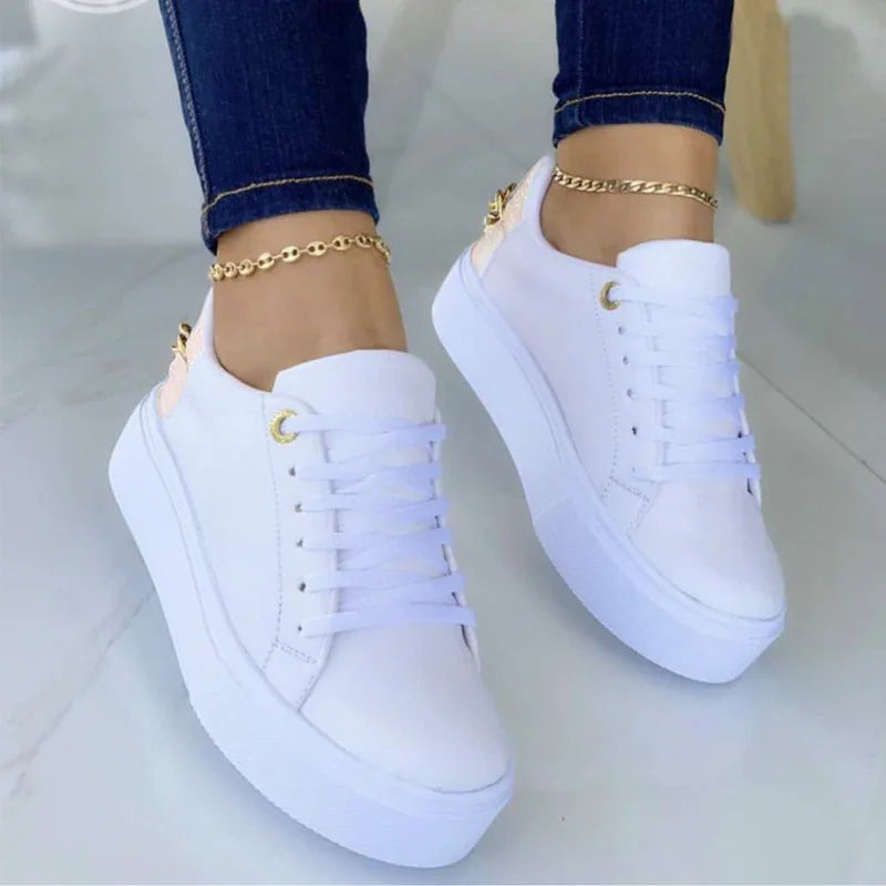White platform sneakers worn with dark skinny jeans and gold anklets on a light floor