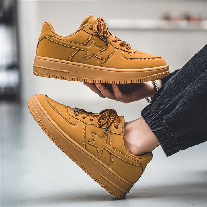 Brown leather sneakers with star logo, thick sole, and patterned laces worn with black pants