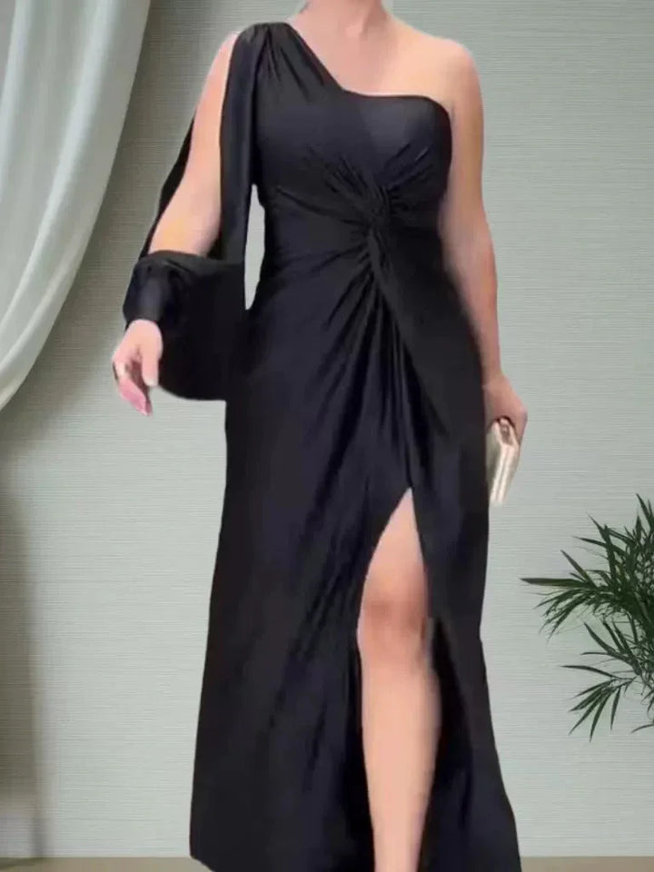 Woman wearing black one-shoulder evening gown with thigh-high slit holding a clutch handbag