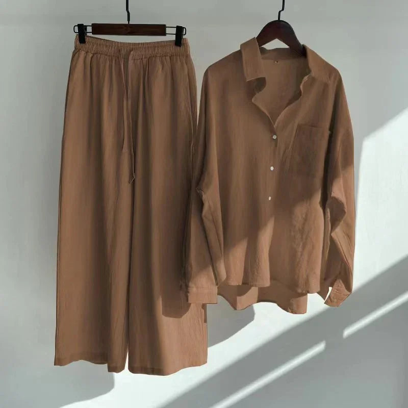 Brown loose pants with elastic waist and matching button-up shirt hanging on wooden hangers