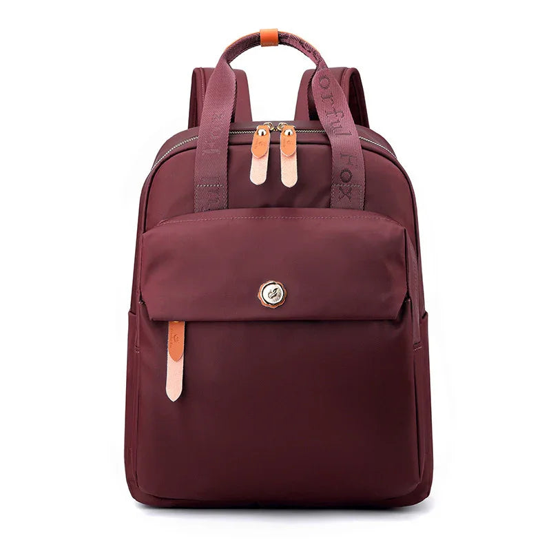 Maroon nylon backpack with front pocket, leather zipper pulls, and adjustable shoulder straps