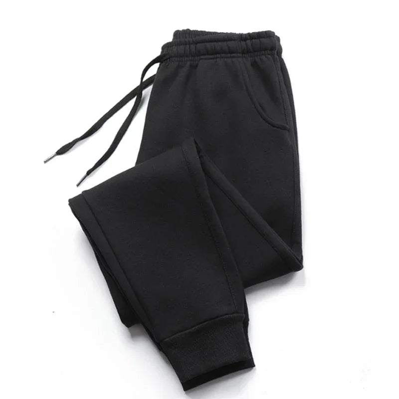 Black fleece sweatpants with drawstring waist and cuffed ankles folded on white background