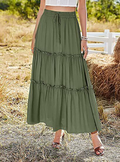 Woman wearing olive green tiered maxi skirt with drawstring waist, standing outdoors in sunny field