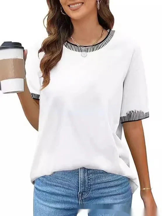 Woman wearing white short sleeve t-shirt with black striped collar and sleeve cuffs, holding coffee cup, blue jeans
