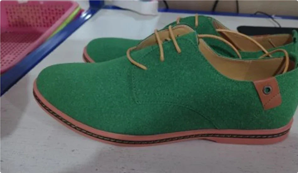 Pair of green suede casual men's shoes with brown laces and trim on white surface