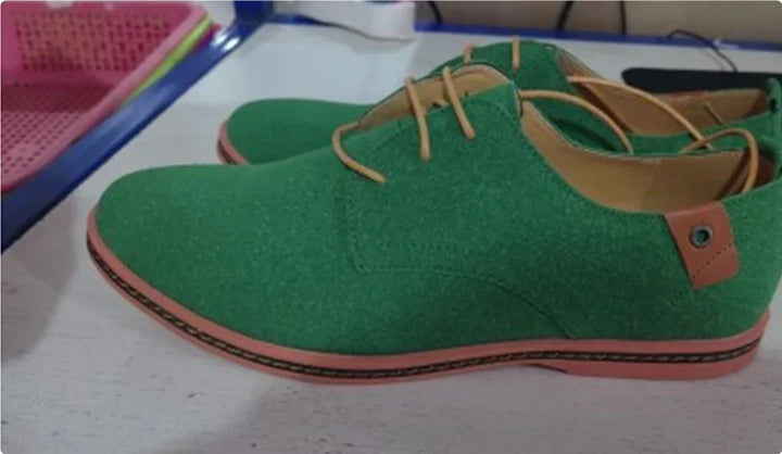 Pair of green suede casual men's shoes with brown laces and trim on white surface