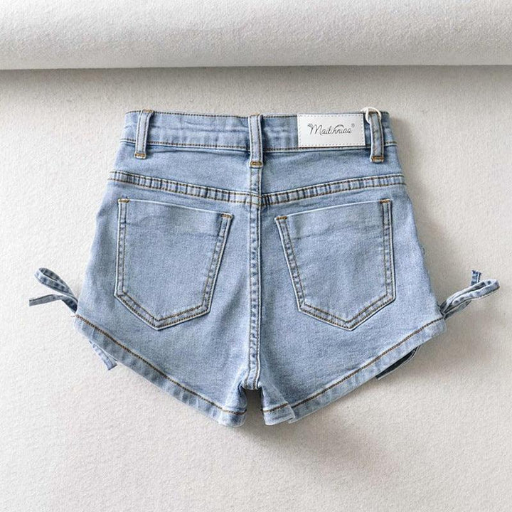 Light blue high-waisted denim shorts with back pockets and side ties on white background