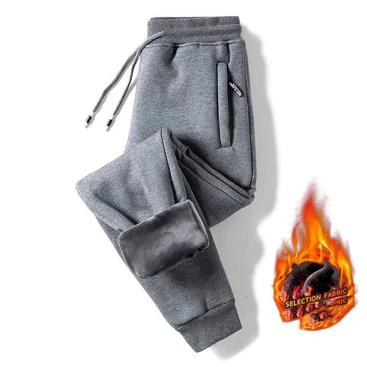 Grey fleece-lined sweatpants with drawstring waist and zippered pockets on white background