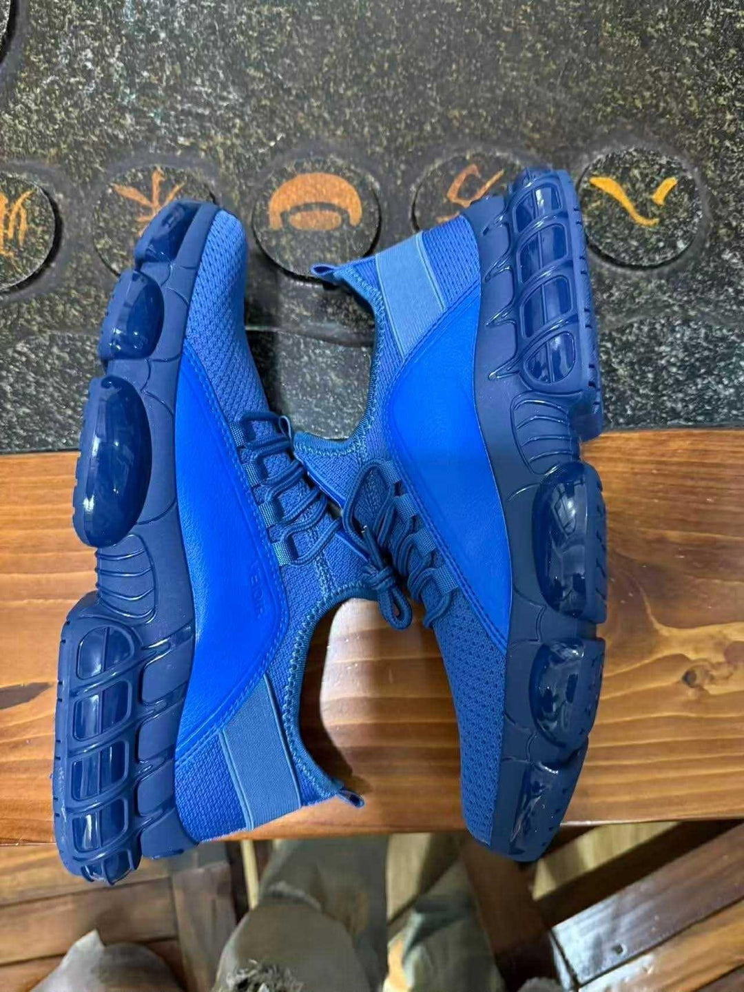 Pair of blue athletic sneakers with breathable mesh and cushioned soles on wooden surface