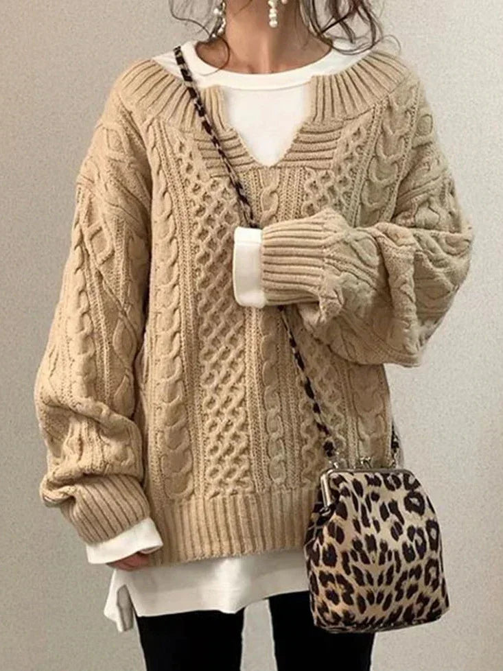 Woman wearing beige chunky cable knit sweater with white shirt underneath and leopard print crossbody bag