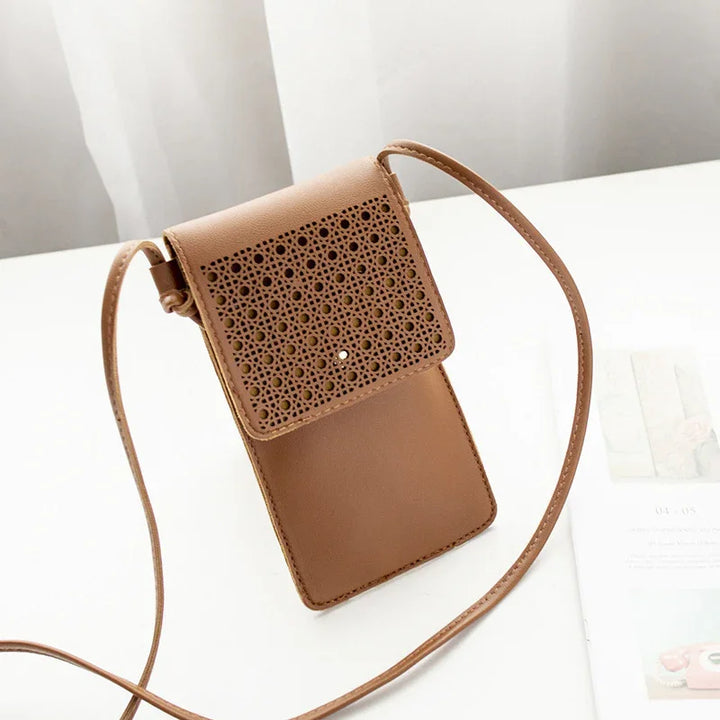 Brown leather crossbody bag with intricate perforated flap on white surface