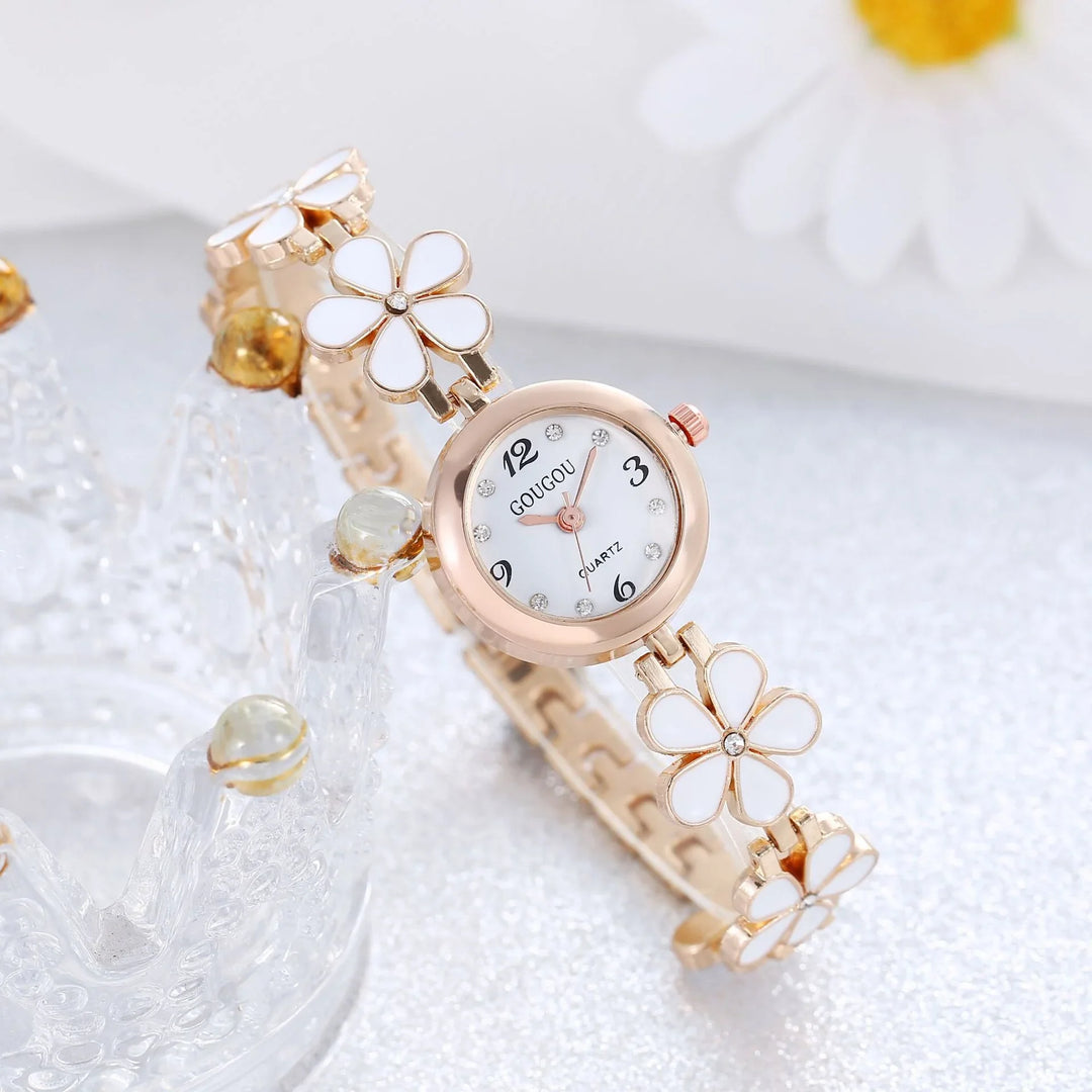 Rose gold women's wristwatch with white flower bracelet and crystal accents on silver background