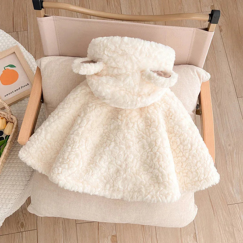 Cream-colored fluffy toddler cape with hood and bear ears on wooden chair with cushion