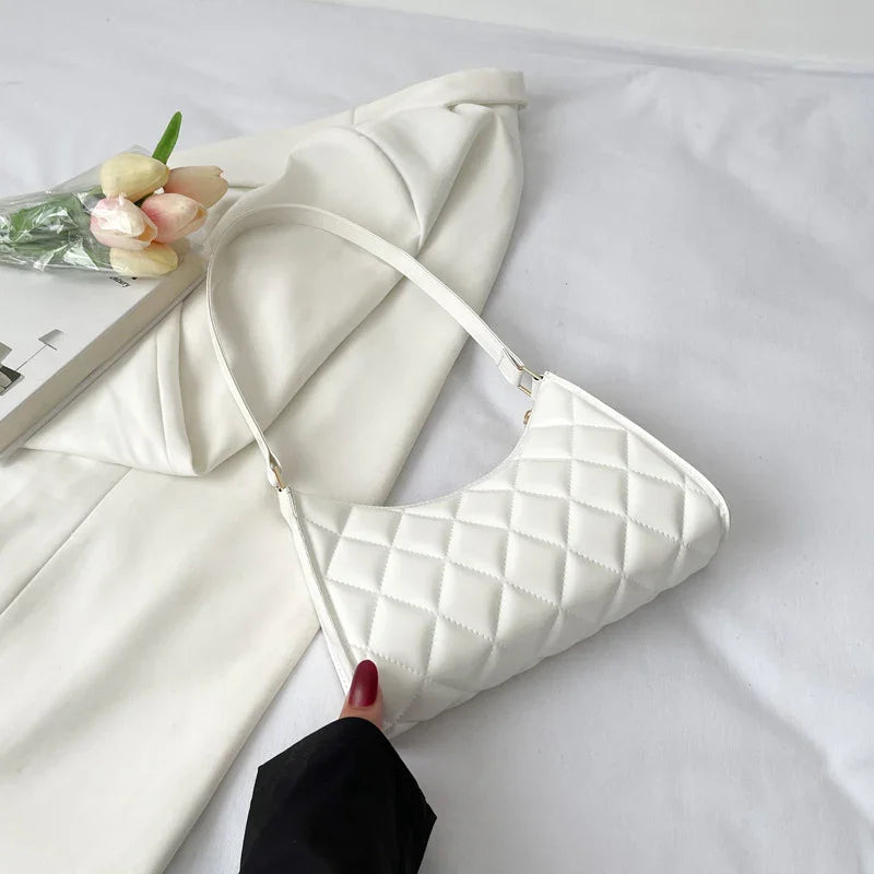 White quilted shoulder bag held above cream blazer with tulip bouquet on white background
