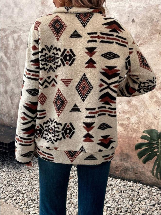 Woman wearing beige fleece jacket with red and black geometric tribal patterns outdoors