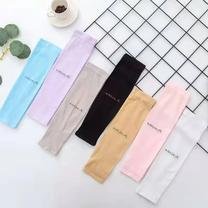 Seven pairs of Aqua-X brand arm sleeves in pastel and neutral colors laid out on white surface with decorative leaves and coffee cup