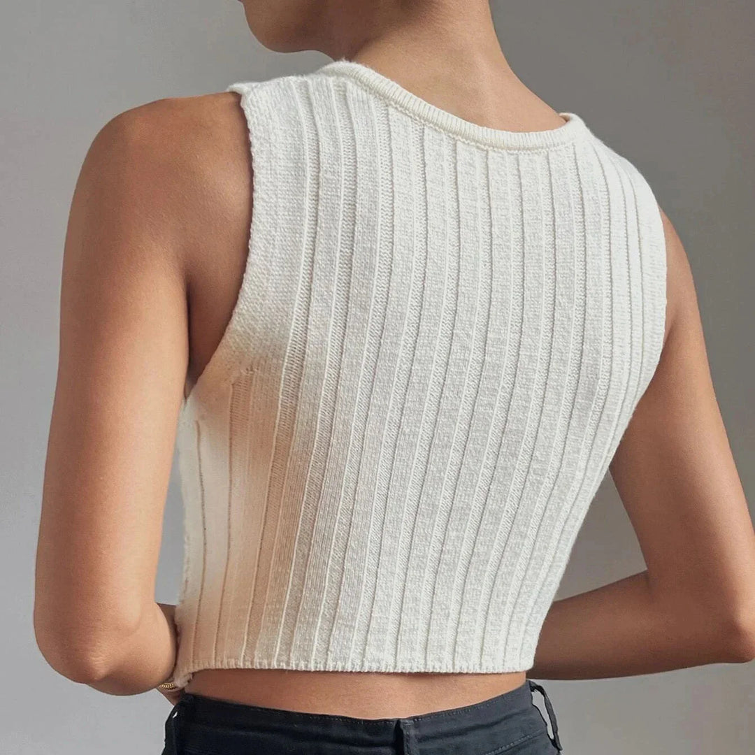 Back view of woman wearing a white ribbed sleeveless knit crop top with black pants