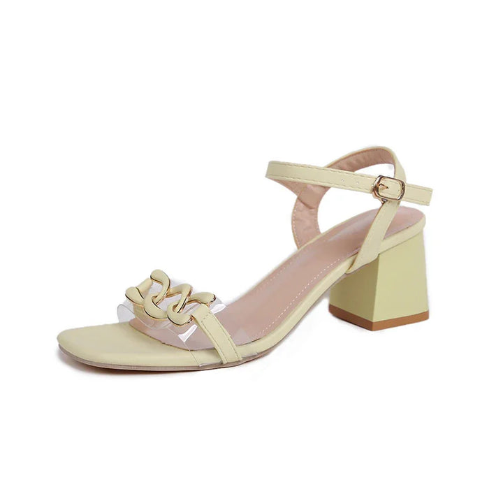Elegant pale yellow block heel sandal with ankle strap and decorative gold chain on front