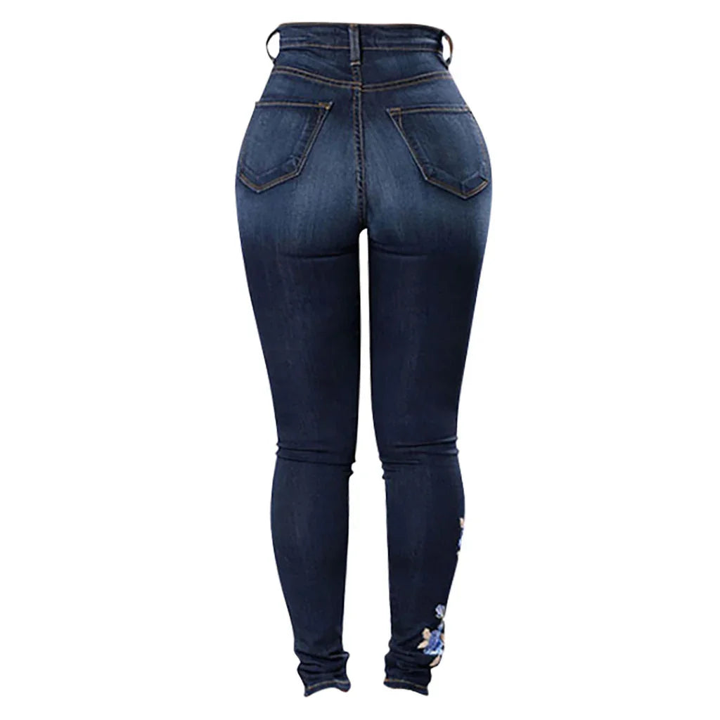 Back view of dark blue high-waisted skinny jeans with stitched pockets and floral embroidery near ankle