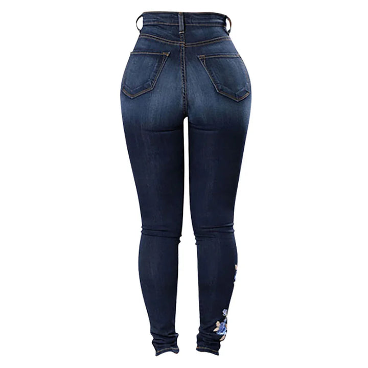 Back view of dark blue high-waisted skinny jeans with stitched pockets and floral embroidery near ankle