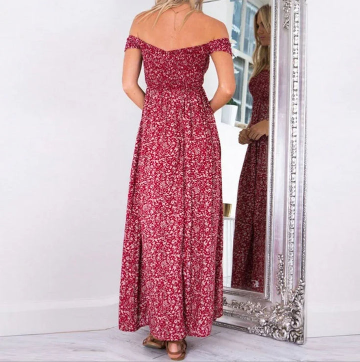 Woman wearing a red floral off-shoulder maxi dress standing in front of an ornate silver mirror