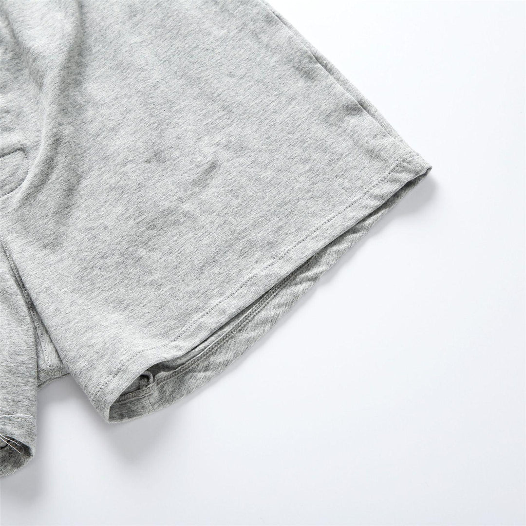 Close-up of light grey cotton shorts fabric with visible hem and stitching detail