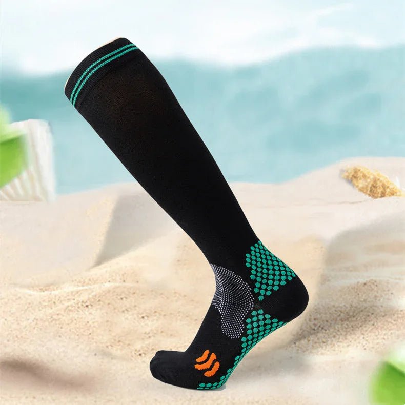 Black compression sock with turquoise and orange accents displayed on sandy beach background
