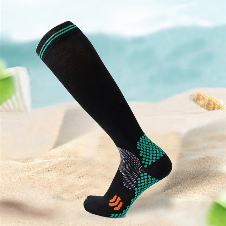 Black compression sock with turquoise and orange accents displayed on sandy beach background