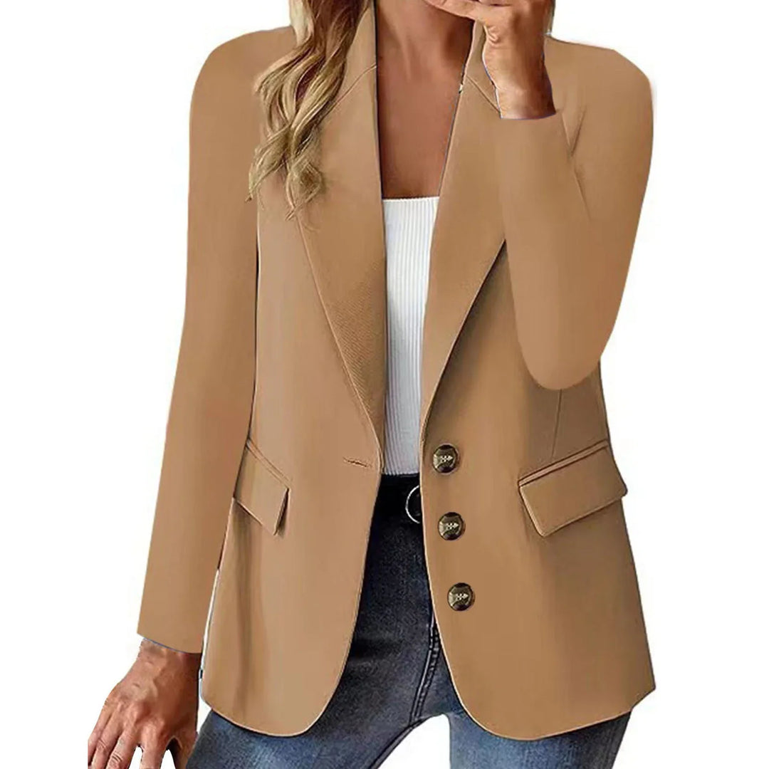 Woman wearing camel brown blazer with lapels, button closure, and flap pockets over white top and jeans