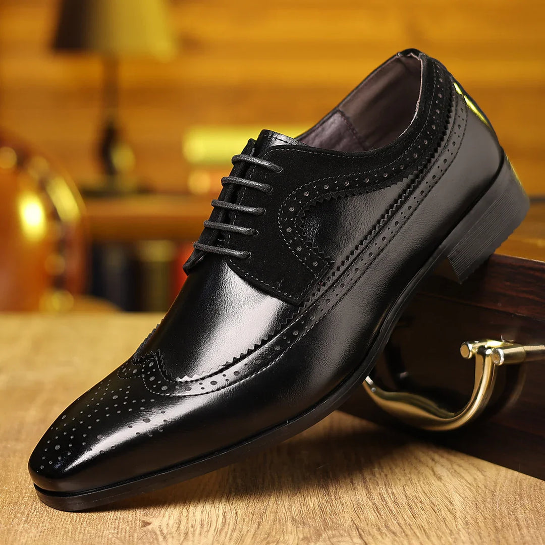 Black leather brogue dress shoe with detailed perforations and laces on wooden surface