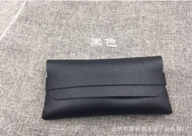 Black textured leather eyeglass case on gray fabric background with white Chinese text