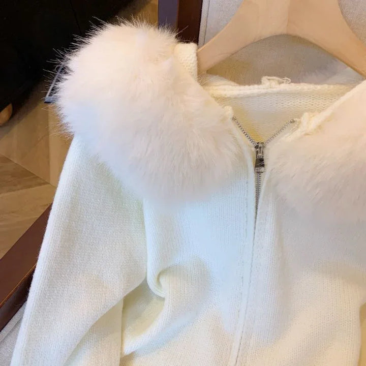 White knitted sweater with fluffy faux fur collar and silver zipper on wooden hanger