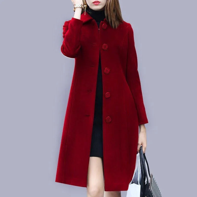 Woman wearing a stylish long red buttoned coat with black dress, holding black and white handbag