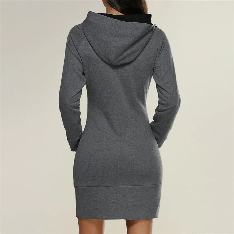 Woman wearing grey long-sleeve hooded sweatshirt dress, back view on plain light background