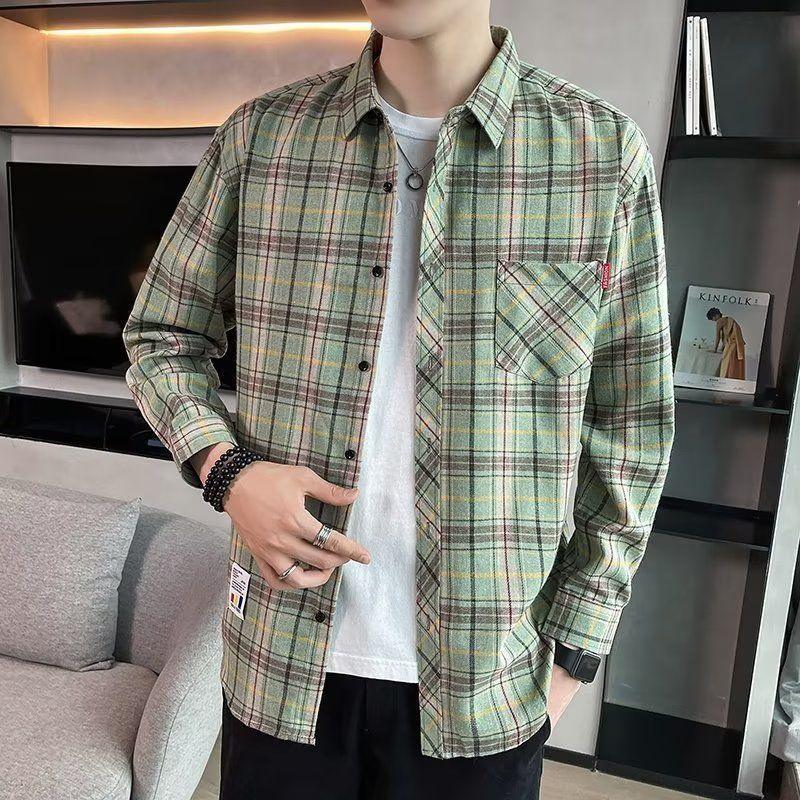 Man wearing green and yellow plaid button-up shirt over white t-shirt, casual indoor setting